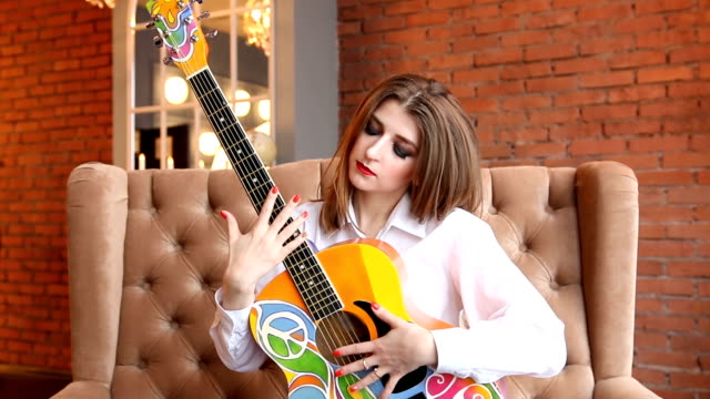 Mädchen-in-weißen-Hemd-posiert-mit-einer-Gitarre-im-Hippie-Stil