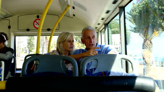 Senior-pareja-interactuando-con-los-demás-mientras-viaja-en-autobús-4k