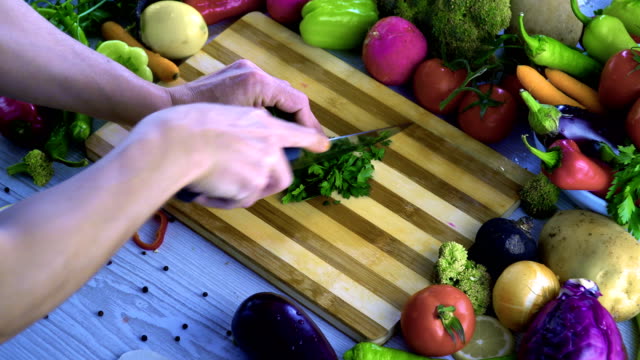 Man-is-chopping-parsley-on-cutting-board-in-the-kitchen