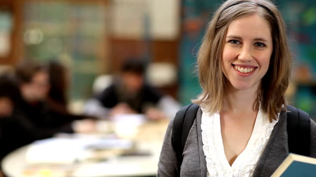 Eine-nette-weibliche-College-Student-schaut-in-die-Kamera-und-das-Lächeln