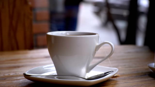 Weiße-Tasse-heißen-Tee-auf-dem-Tisch-in-einem-Cafe-auf-dem-Hintergrund-des-Fensters-Straße