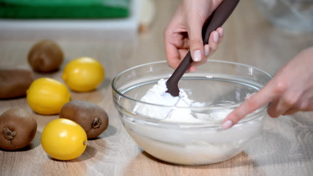 Female-hands,-mix-the-cream-in-the-glass-bowl-with-spatula.