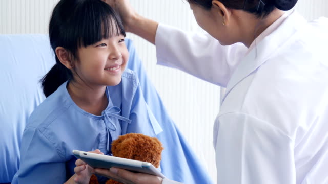 Doctor-visiting-Little-Girl-in-the-Hospital,-Little-Girl-looking-to-tablet-with-doctor-together-in-hospital.-People-with-Technology,-Healthcare-and-Medical-Concept.