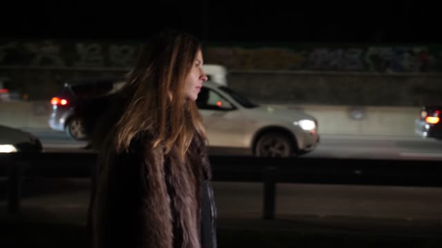 A-beautiful-drunk-woman-goes-along-the-city's-night-road-and-drinks-wine-from-the-bottle-4k-Slow-Mo