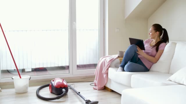 woman-with-tablet-pc-and-tea-after-cleaning-home