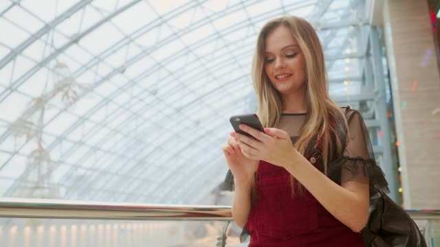 Girl-use-mobile-phone,-blur-image-of-inside-the-mall-as-background