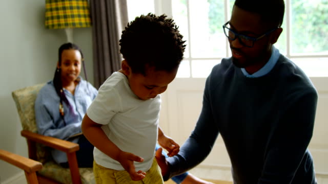 Front-view-of-young-black-father-playing-with-his-son-in-living-of-comfortable-home-4k
