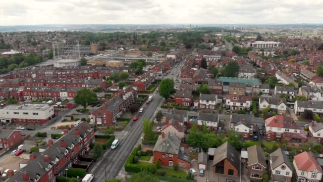 Aerial-footage-of-the-town-known-as-Crossgates-in-the-Leeds-Area-of-West-Yorkshire-in-the-UK,-showing-a-typical-British-town-and-street-with-rows-of-houses-and-light-traffic-on-the-main-roads.