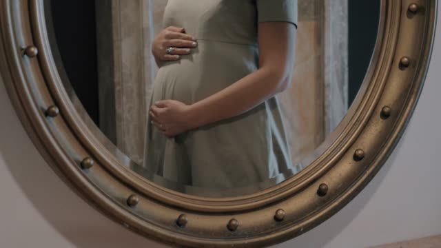 Pregnant-woman-touching-belly,-mirror-reflection