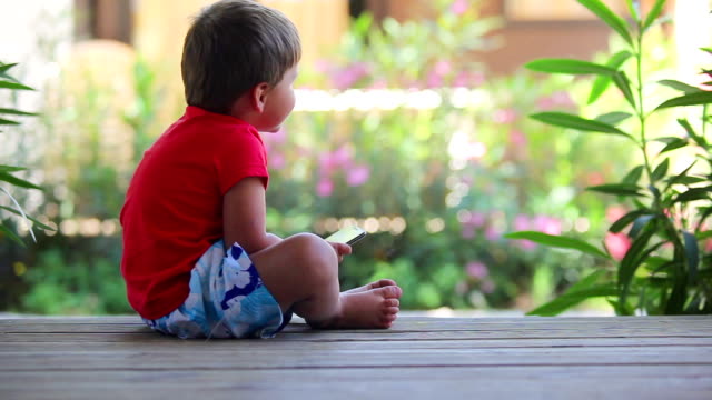 Boy-sits-on-the-porch-and-plays-with-mobile-phone