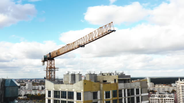 Drone-flying-close-around-construction-crane-during-development-process-of-high-rise-tower-block-apartment-building.