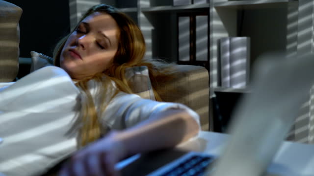Müde-Geschäftsfrau-schlafend-auf-der-Couch-im-Büro-mit-Laptop-und-Telefon-in-der-Nacht
