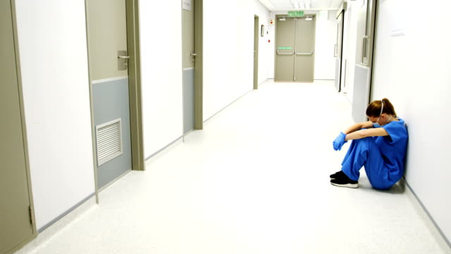 Tensed-female-doctor-sitting-in-corridor