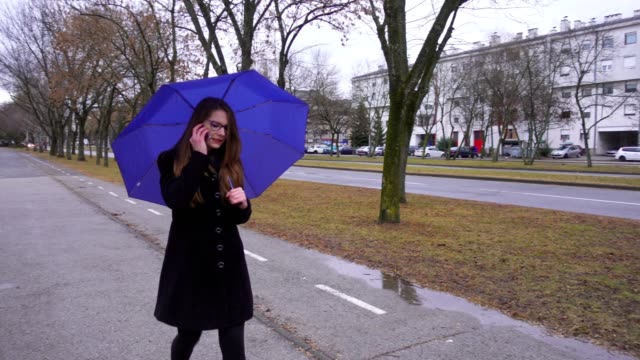 Young-woman-with-umbrella-using-smartphone