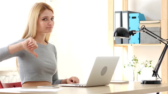 Thumbs-Down,--Woman-Gesturing-while-Sitting-in-Office