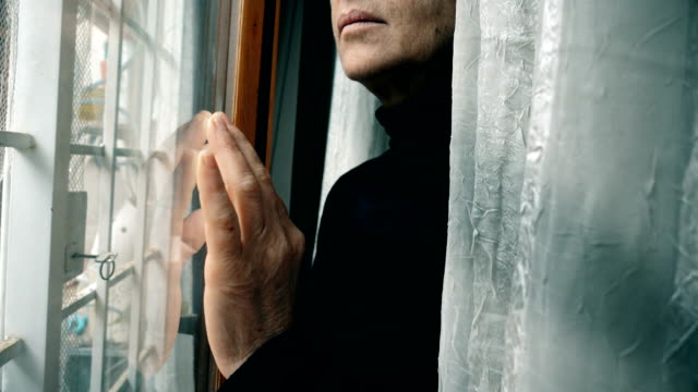 Close-up-on-hand-of-mature-woman-leaning-against-window