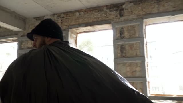 Hombre-sin-hogar-con-bolsa-de-basura-a-pie-en-edificio-abandonado
