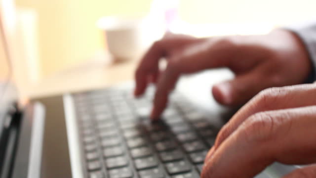 businessman-typing-on-a-laptop-keyboard-in-blurred-focus