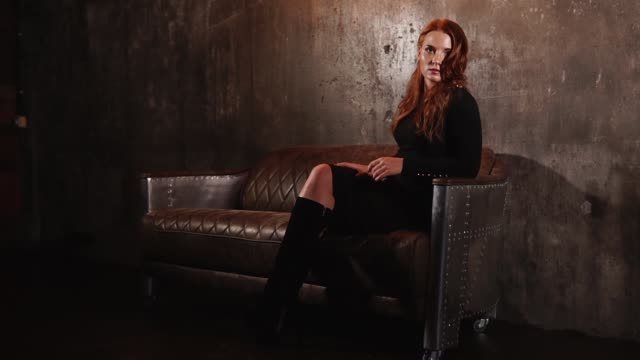 beautiful-red-haired-elegant-woman-sitting-on-a-leather-sofa