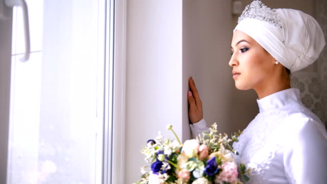 Wunderschöne-muslimische-Braut-mit-Make-up-sieht-aus-dem-Fenster-und-lächelt
