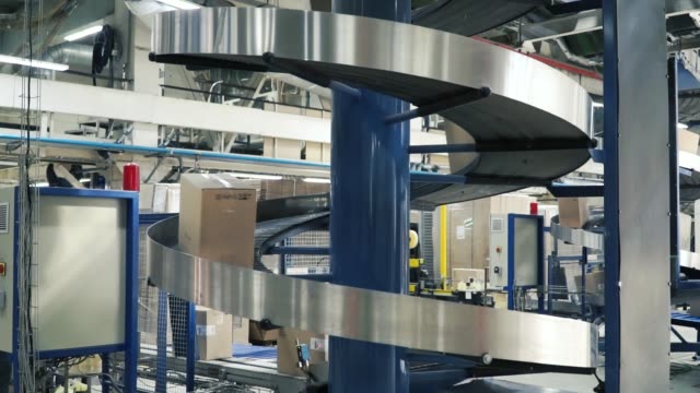 Cardboard-boxes-on-conveyor-belt-in-factory.-Clip.-Production-line-on-which-the-boxes-move-in-a-spiral