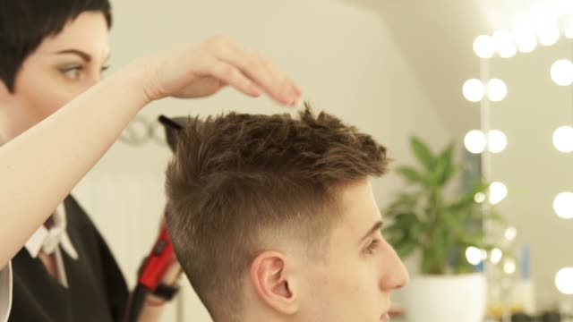 Hairdresser-drying-and-styling-male-hair-after-cutting-in-hairdressing-salon.-Close-up-barber-styling-hair-with-dryer-after-washing.-Finish-hairdressing-in-beauty-studio