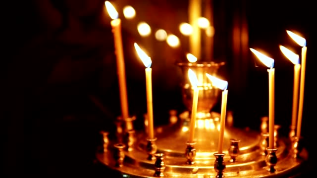 Velas-encendidas-en-candelabros-de-iglesia,-en-el-fondo-de-los-iconos-religiosos