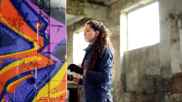 Zwei-Freunde-Graffiti-Maler-zeichnen-abstrakte-Bildern-auf-alte-beschädigte-Spalte-in-verlassenen-Haus-halten-Aerosol-Lack.-Kreative-Menschen-sind-auf-ihre-Arbeit-konzentriert.