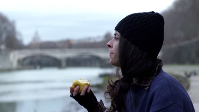 junge-Obdachlose-Frau-isst-einen-Apfel-und-jemand-grüßt