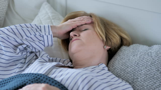 Verärgert-Senior-alte-mit-Kopfschmerzen-im-Bett-schlafen