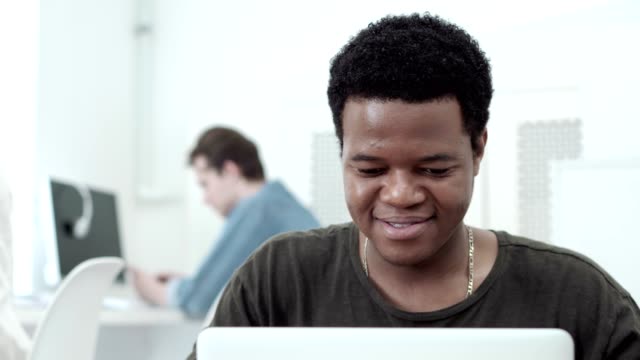 Emotional-African-man-smiling-and-laughing-while-texting-in-social-network-in-Internet-cafe