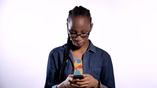 Junge-afrikanische-Amerikanerin-in-Gläsern,-die-Eingabe-auf-Telefon,-isoliert-auf-weißem-Hintergrund,-Ernst-und-konzentriert
