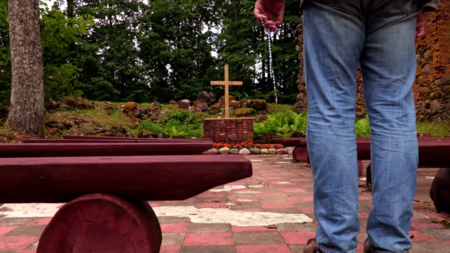 Mann-mit-Rosenkranz-zu-beten-gehen-in-der-Nähe-von-Kreuz