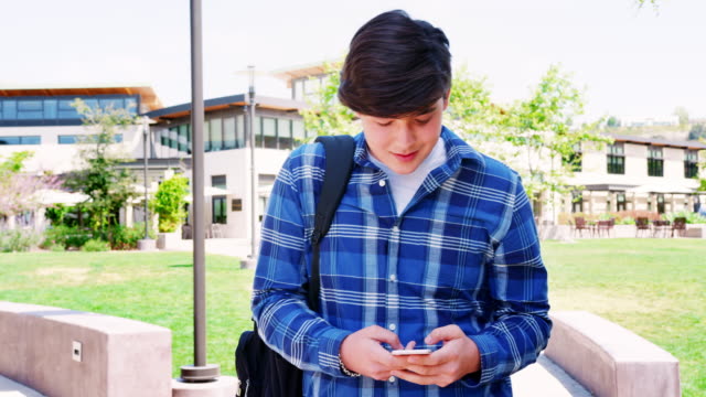 Männlichen-High-School-Schüler,-die-Nachrichten-auf-Mobile-Telefon-außen-College-Gebäuden