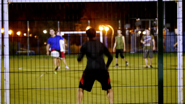 In-the-foreground-is-the-goalkeeper,-another-young-man-kicks-the-ball-and-hits-the-goal,-night-shooting