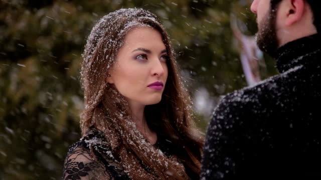 Couple-in-black-clothes-under-heavy-snow.-Wedding.