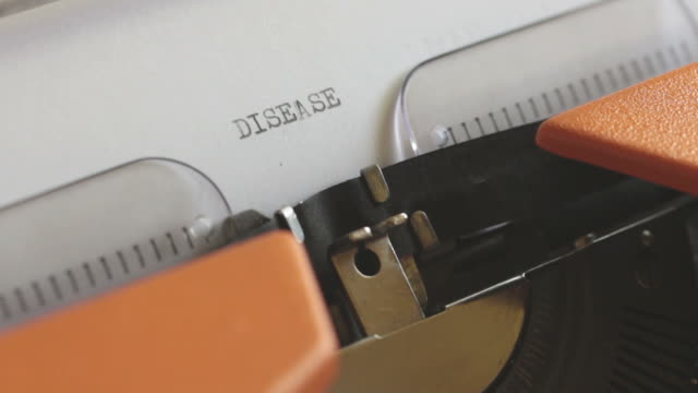 Close-up-footage-of-a-person-writing-DISEASE-on-an-old-typewriter,-with-sound