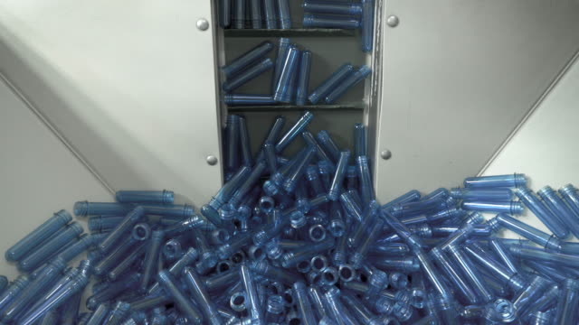 Big-pile-of-small-blue-blanks-lifting-up-on-the-factory-line-to-create-plastic-bottles.