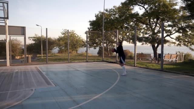 Szene-von-einem-weiblichen-Basketball-Spieler-üben-in-wirft-den-Ball-auf-den-Reifen-auf-dem-lokalen-im-freien-Basketballplatz.-Übersicht-Filmmaterial