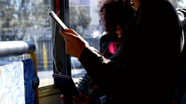 Madre-e-hija-con-tableta-digital-mientras-viaja-en-autobús-4k