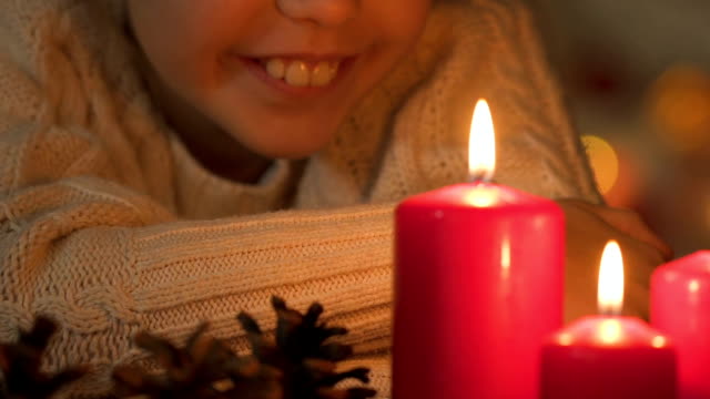 Glückliches-Kind-betrachtet-man-brennende-Kerzen,-warten-auf-das-Wunder-von-Weihnachten-closeup