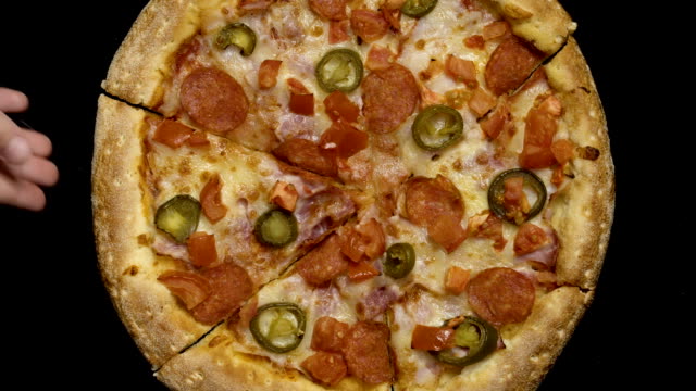 Hand-nimmt-ein-Stück-Pizza-auf-einem-schwarzen-Hintergrund