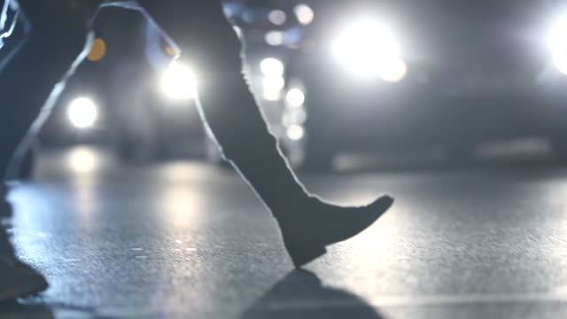 Pedestrians-feet-crossing-street-at-night-with-lens-flares-hitting-camer-ain-the-background