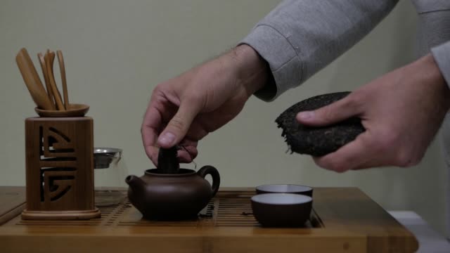 Ich-breche-Puer-Tee-und-legen-Sie-es-in-einem-Ton-Teekanne.-Chinesische-Tee-Zeremonie.