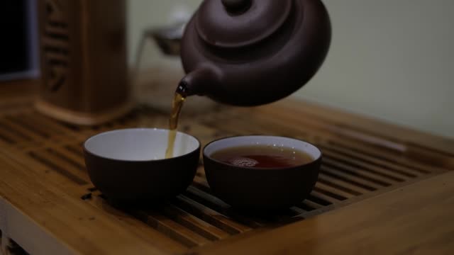 Ich-gieße-Tee-aus-einem-Steingut-Teekanne-in-Schalen.-Chinesische-Tee-Zeremonie.
