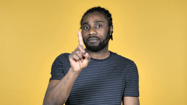 Casual-African-Man-Waving-Finger-to-Refuse-Isolated-on-Yellow-Background