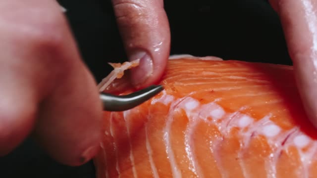 Chef-nimmt-Knochen-vom-Lachs-Filet-schneiden-Fisch-auf-Scheiben-zum-Kochen-Sushi-in-4-k-Auflösung-in-Zeitlupe