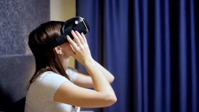 Schöne-junge-Frau-tragen-VR-Kopfhörer-im-Schlafzimmer-und-schaut-sich-um.-VR-Video-Nahaufnahme-ansehen.