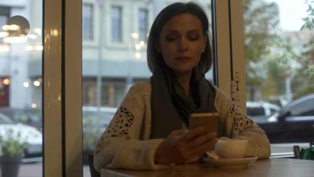 Elegante-Dame-im-Café-sitzen,-Tee-trinken-und-Beantwortung-von-E-mails-auf-smartphone