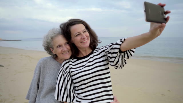 Erwachsene-Tochter-umarmt-und-senior-Mama-Selfie-mitnehmen